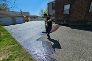 A residential driveway being sealcoated by a Superior Sealcoating employee - Superior Sealcoating in Collegeville, PA - Superior Sealcoating