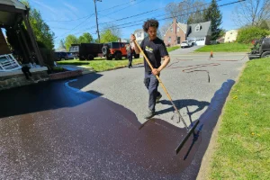 A residential driveway being sealcoated by a Superior Sealcoating employee - Superior Sealcoating in King of Prussia, PA - Superior Sealcoating