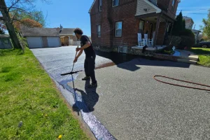 A residential driveway being sealcoated by a Superior Sealcoating employee - Superior Sealcoating in Limerick, PA - Superior Sealcoating