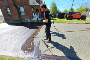 A residential driveway being sealcoated by a Superior Sealcoating employee - Superior Sealcoating in Norristown, PA - Superior Sealcoating