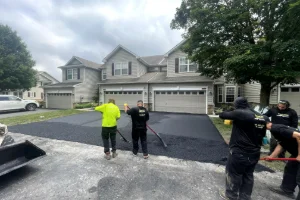 Image of a residential driveway being sealcoated by a worker