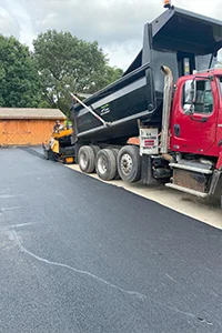 Image of a truck dumping asphalt onto a residential driveway