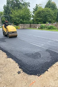 Image of a machine rolling out the asphalt in a parking lot
