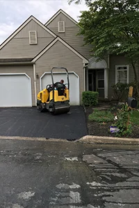 Image of a machine rolling out the asphalt in a residential driveway