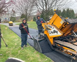 Superior Sealcoating employees paving a residential driveway with paving equipment - Paving in Chester County, PA - Superior Sealcoating